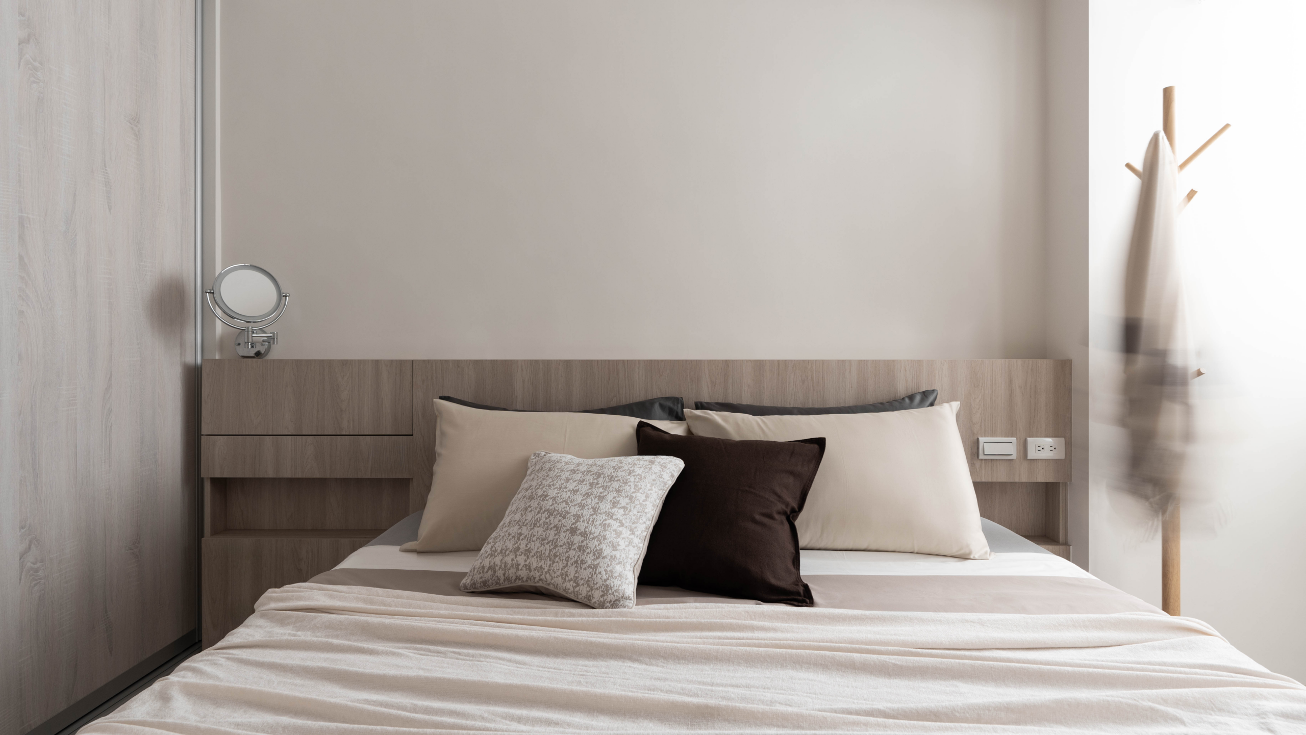 床頭板不僅具備收納功能，其下掀設計可迅速轉換為梳妝台，內部空間適合擺放保養用品，並搭配可收折式帶光圓鏡，方便日常護理作業。