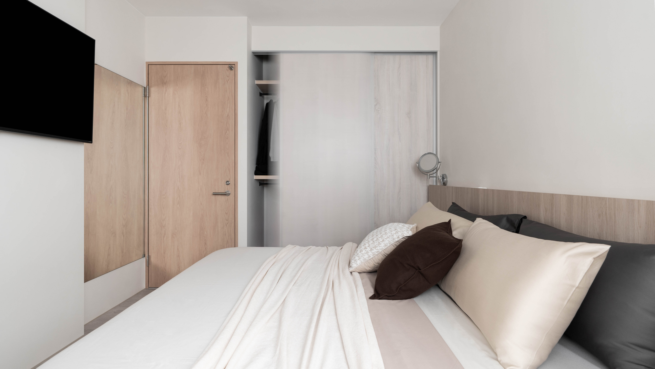 系統門片與木作層板混合設計的拉門衣櫃不僅操作方便，還能靈活加裝抽屜盒，並可收納行李箱及雜物，帶來更多運用上的彈性。